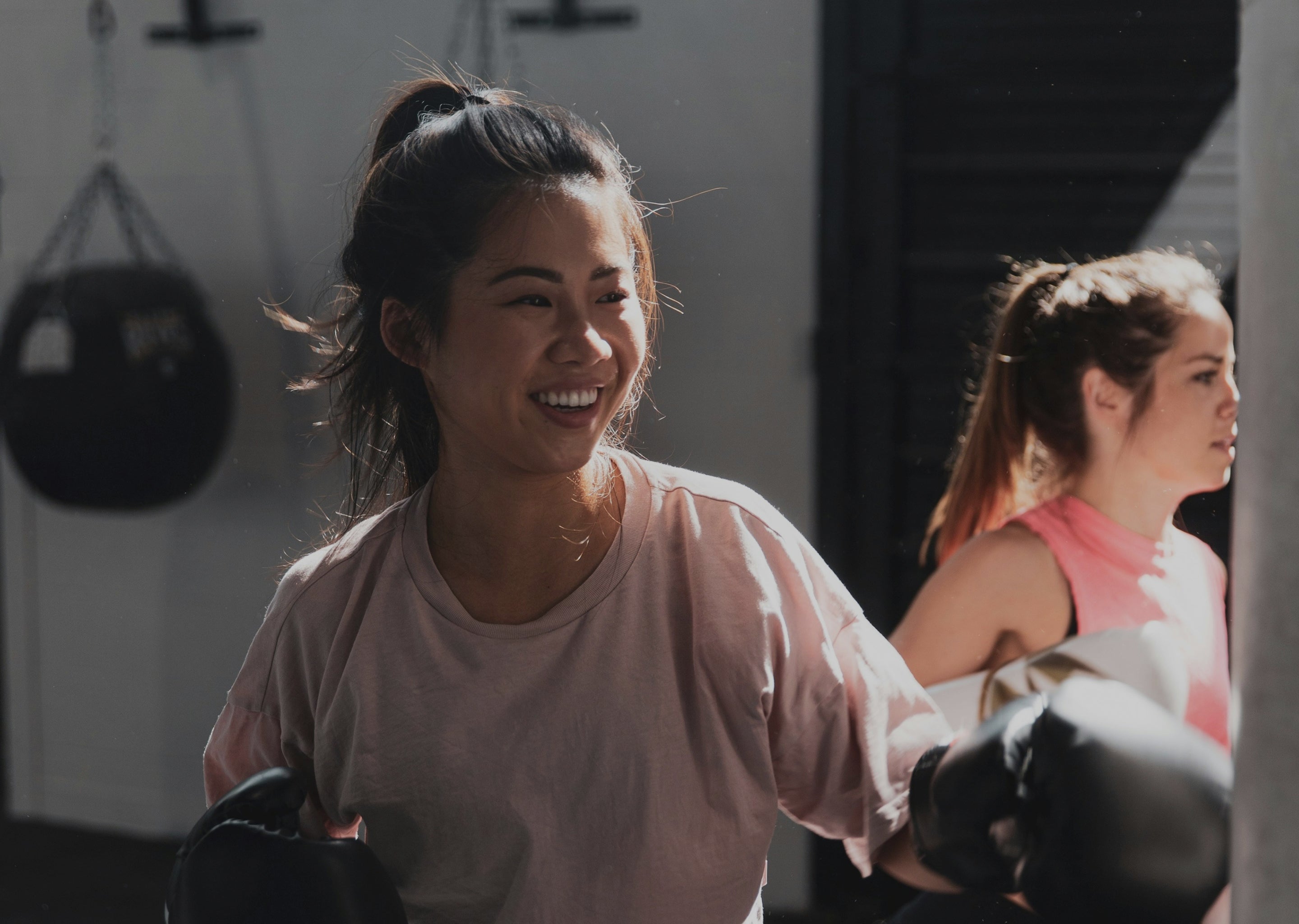 Woman in a gym wearing boxing gloves and smiling